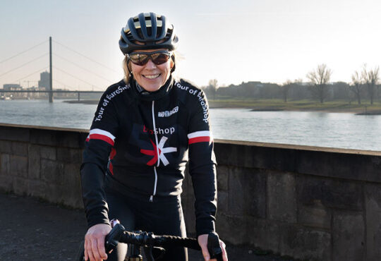 EuroShop-Director Elke Moebius auf ihrem Rennrad am Rhein