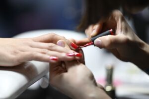 Eine Nail-Designerin widmet sich den Nägeln eines Models
