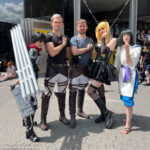 Two cosplayers present their self-made costumes and props.