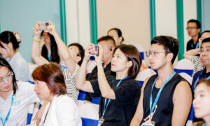 Numerous individuals in the audience are using their smartphones to capture the proceedings
