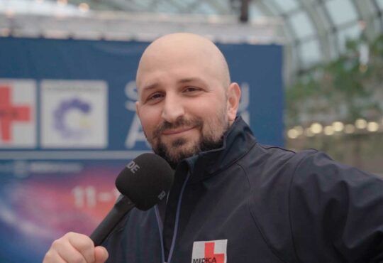 Messe-Mitarbeiter Apostolos Hatzigiannidis mit einem Mikrofon in der Hand auf der Medizintechnik-Messe MEDICA